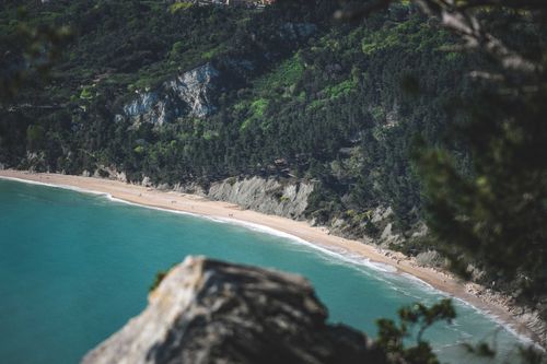 Free A scenic view of a pristine beach surrounded by lush green cliffs. Stock Photo
