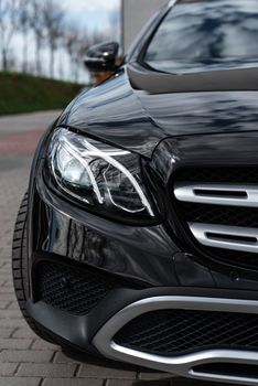 Close-up shot of a black luxury car headlight, showcasing sleek design and elegance.