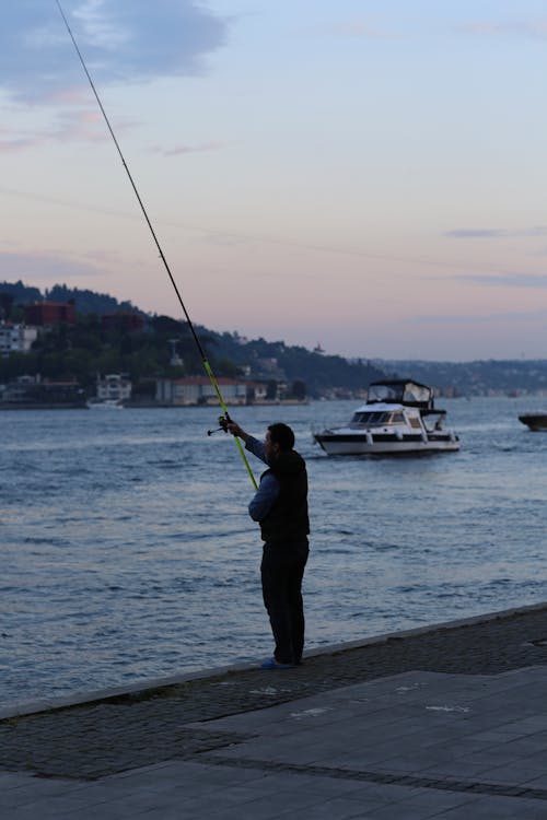 A Man Standing Near the Ocean while Holding a Fishing Rod