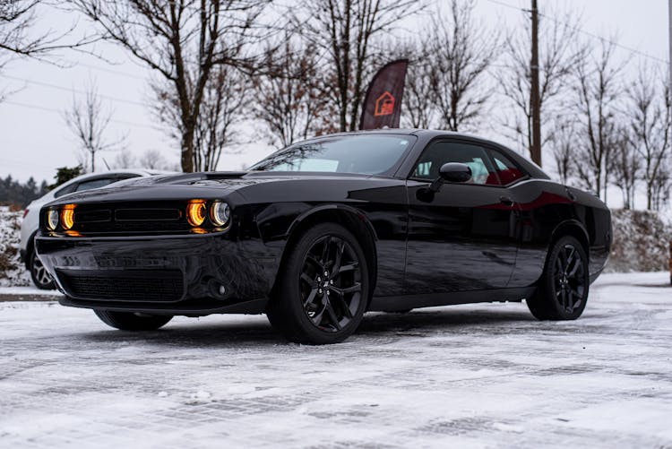 Black Dodge Challenger Parked In A Snow-covered Driveway