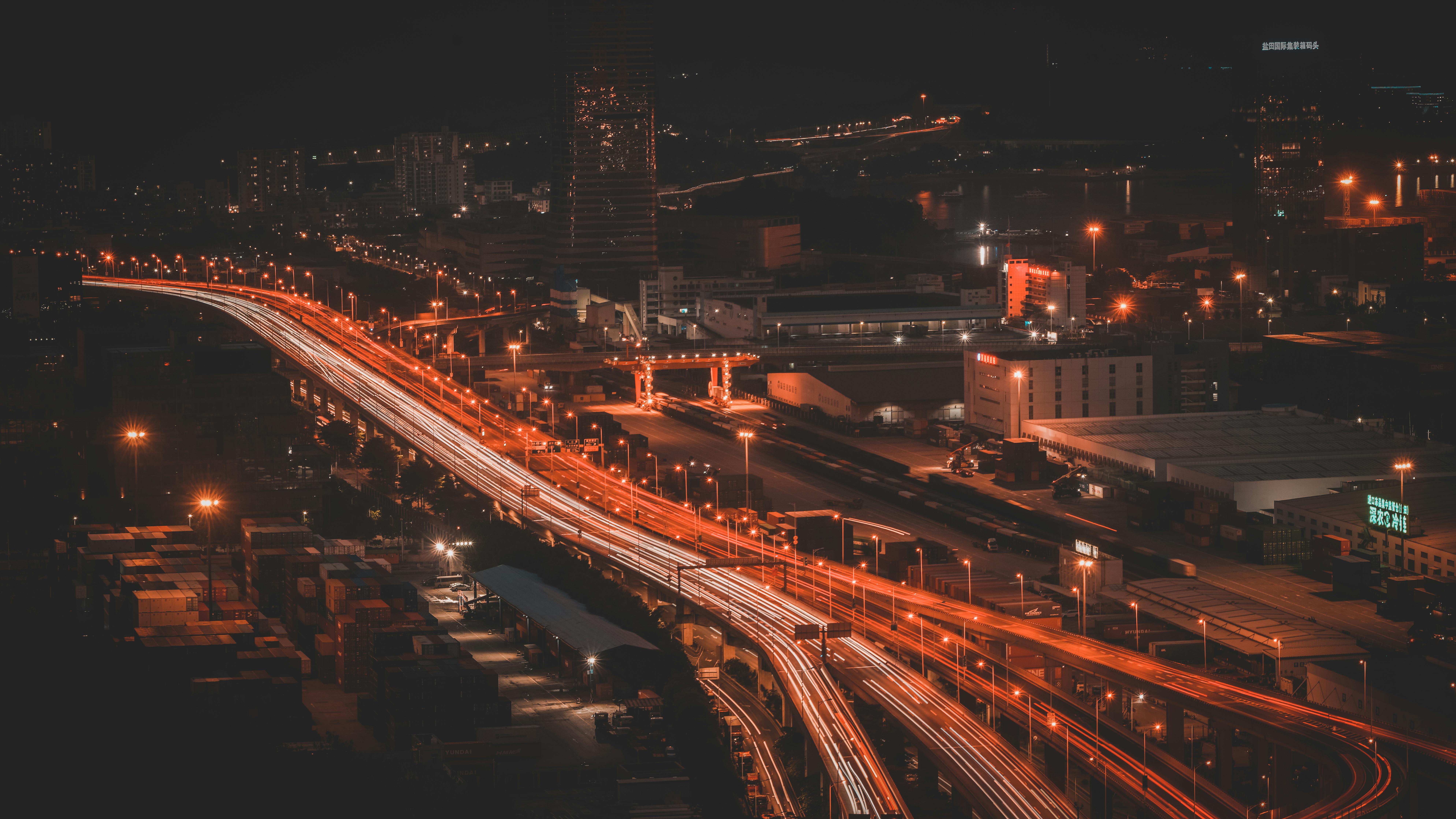 Dynamic aerial view of an urban highway at night with vibrant light trails creating a lively citysca