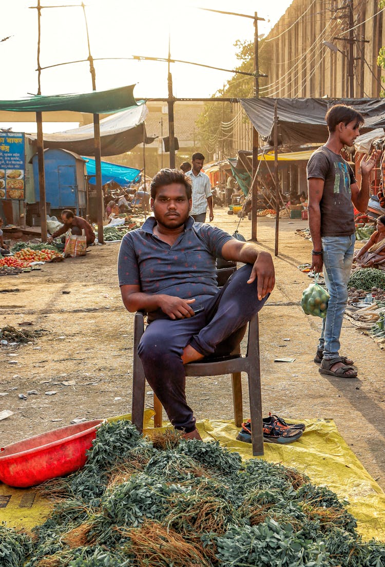 Man Sitting On A Chair Selling Vegetables On A Blanket