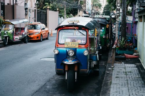 Free A row of vibrant tuk tuks parked along an urban street, showcasing local transportation. Stock Photo