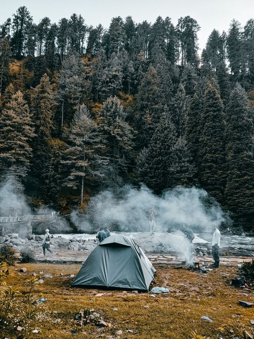 Free A serene campsite in a forest with a tent and campfire. Stock Photo