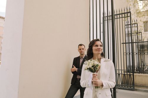 Free A stylish couple poses outdoors with a bouquet, signaling a wedding or engagement moment. Stock Photo
