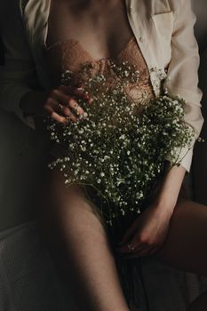 Artistic shot of woman in lingerie holding a bouquet.