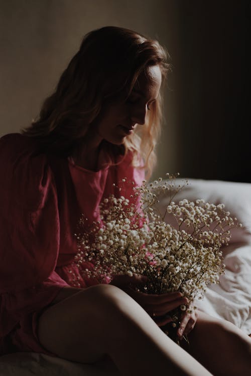 A Woman in a Pink Top Holding Baby's Breath Flowers