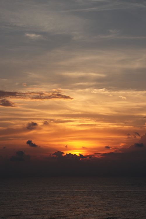 Free Breathtaking sunset over the ocean with a dramatic sky and silhouetted clouds. Stock Photo