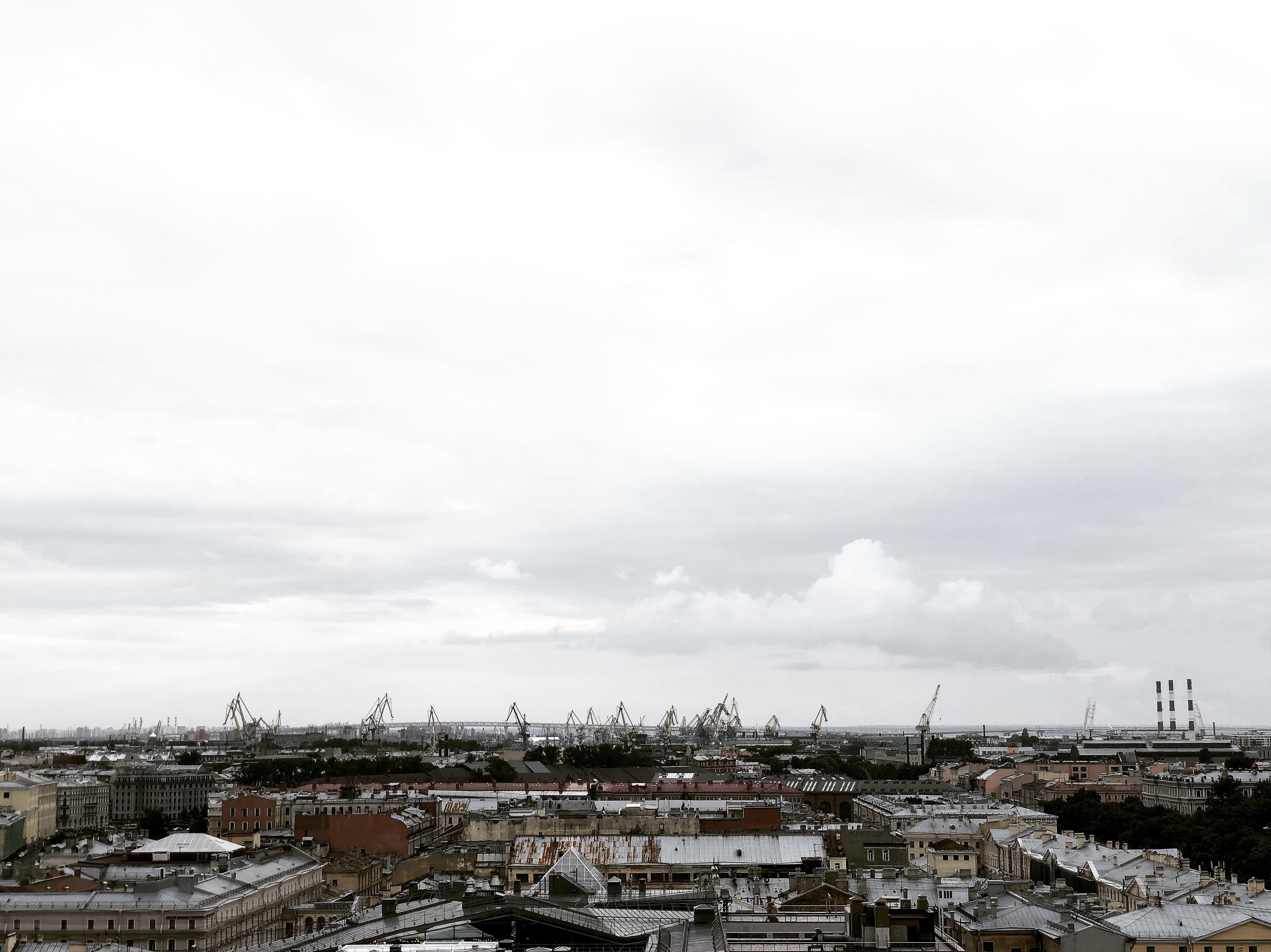 Gloomy skyline view of Sankt-Peterburg, Russia, featuring industrial cranes and cloud-covered sky.