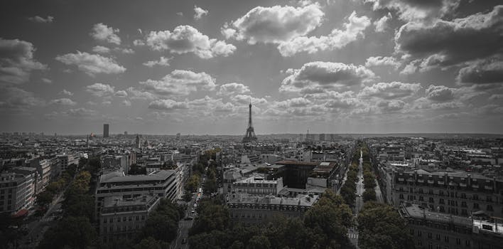 A dramatic aerial view of Paris featuring the iconic Eiffel Tower under a cloudy sky.