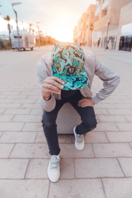 Hombre En Negro Y Verde Floral Ny Cap Sentado En Un Banco De Hormigón