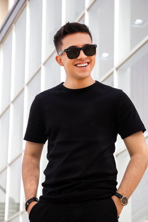 Free Fashionable young man smiling in sunglasses and black t-shirt outdoors. Stock Photo