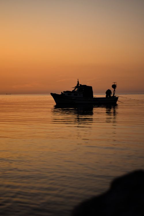 Free A serene silhouette of a boat on calm waters at sunset in Zonguldak, Turkey. Stock Photo