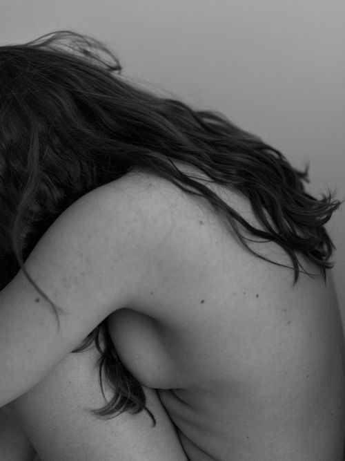 Free Artistic black and white photo of a woman with long hair in a serene, curled position. Stock Photo