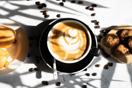 Free Top view of a latte with coffee beans and snacks on a table with shadows. Stock Photo