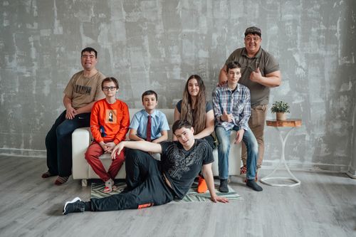 Free Group of seven people posing casually in a stylish indoor setting with a concrete wall background. Stock Photo