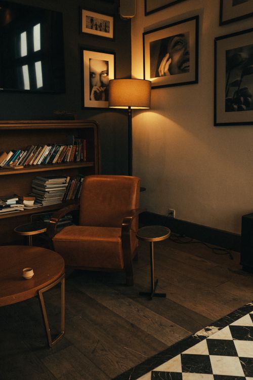 Free Warm interior design featuring a leather chair, bookshelf, and floor lamp. Stock Photo