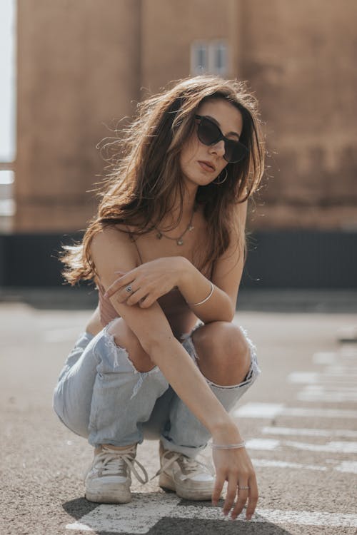 Free Woman in White Dress Wearing Black Sunglasses Sitting on the Ground Stock Photo