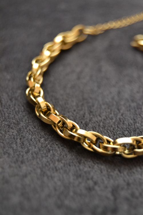 Free Close-up of a shimmering gold chain necklace on a textured dark surface. Stock Photo