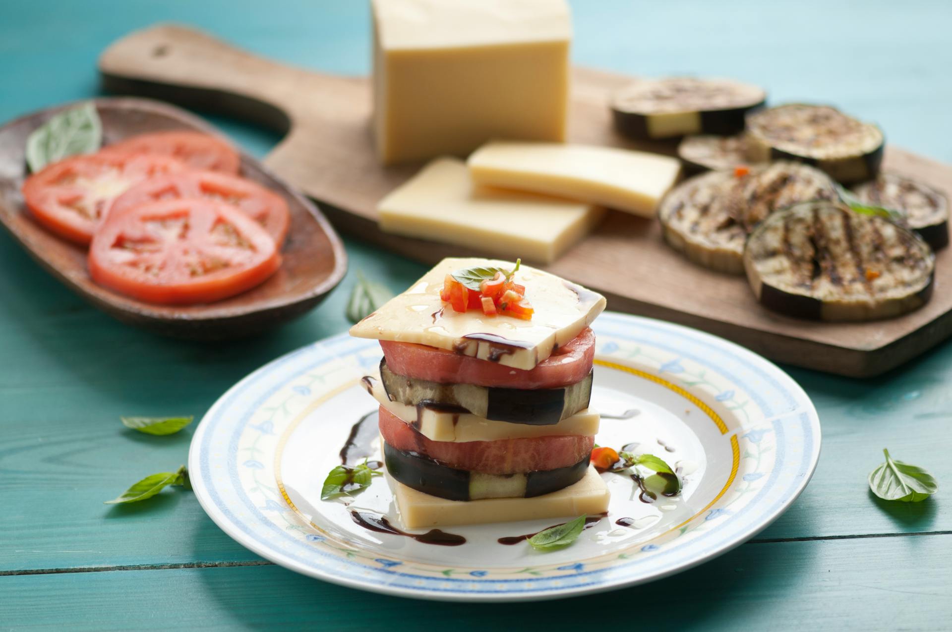 Delicious gourmet plate featuring cheese and vegetable stack with balsamic glaze, showcasing food styling.