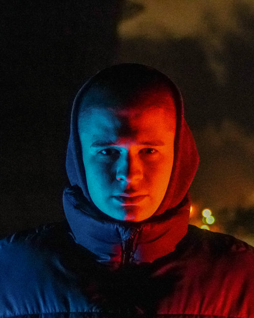 Free Mysterious portrait of a man in a hoodie with colorful lighting outdoors at night in Saint Petersburg. Stock Photo