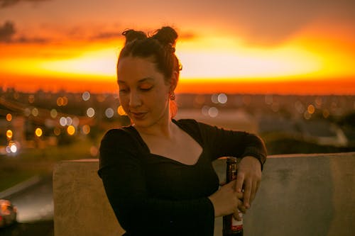 A Woman in Black Long Sleeves Holding a Beer Bottle