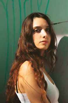 A stylish young woman with long hair poses confidently outdoors, exuding natural beauty.