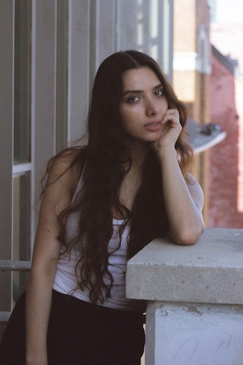 A Woman in White Tank Top with Her Hand on Her Chin