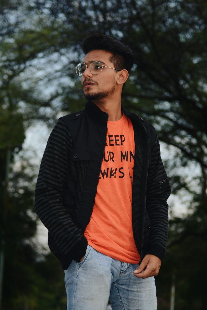 Stylish South Asian man in glasses wearing casual outfit outdoors.