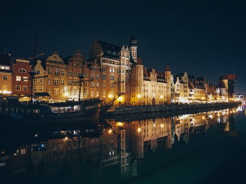 Free Stunning night view of Gdańsk's historic waterfront architecture beautifully reflected in the water. Stock Photo