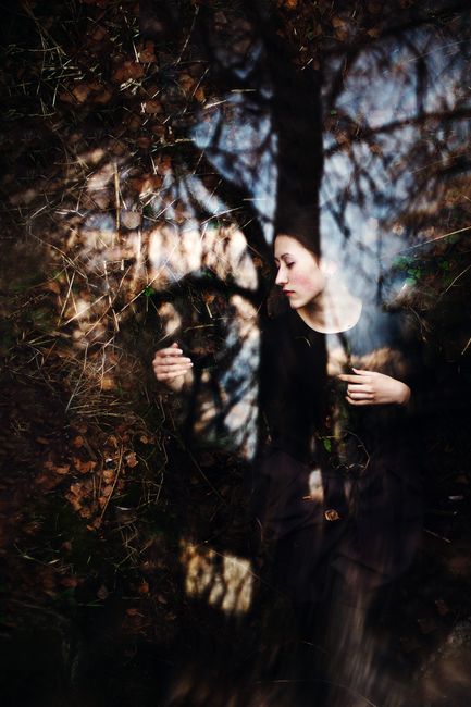 Surreal portrait of a woman superimposed with autumn leaves and branches, conveying a dreamlike forest ambiance.
