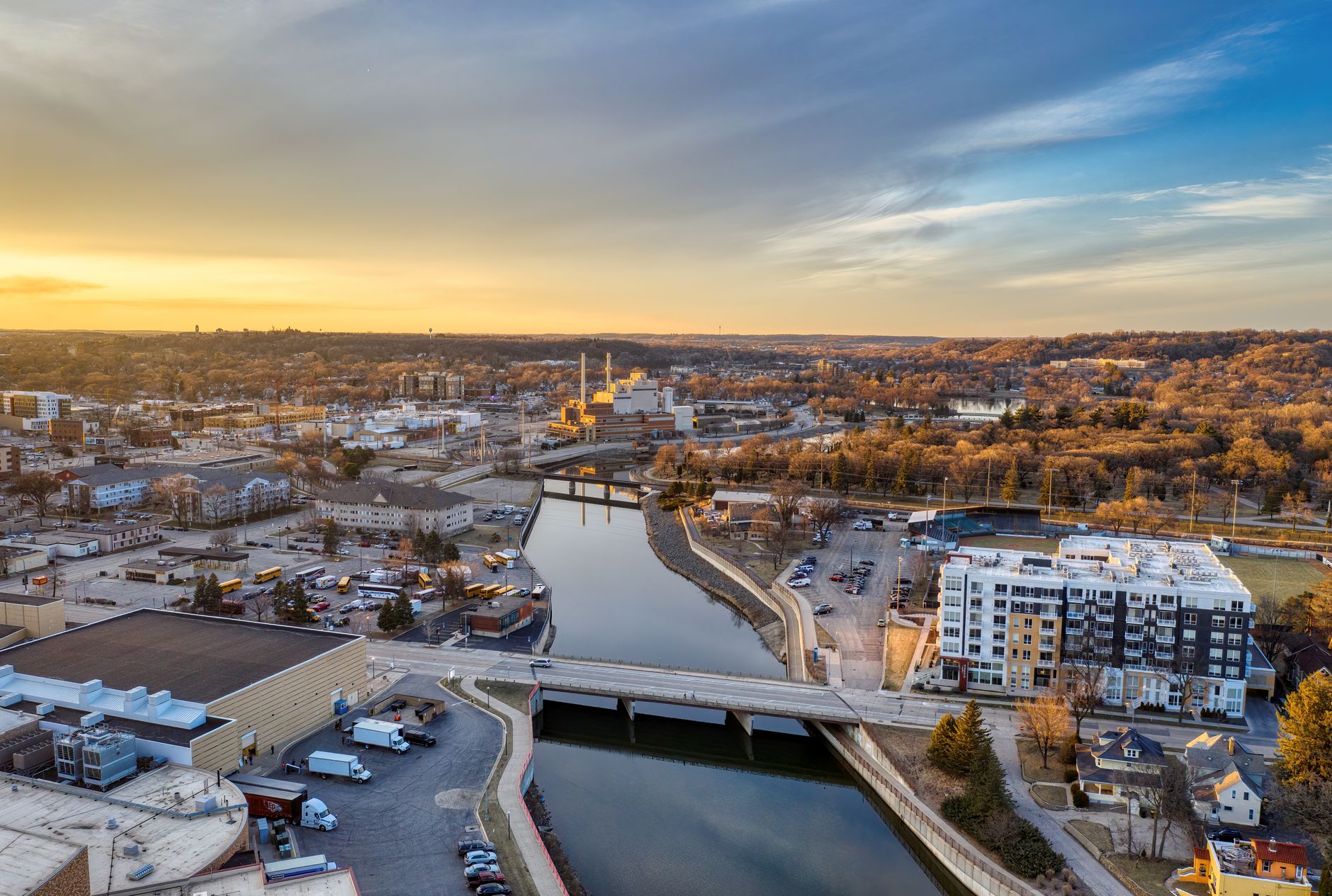 Aerial shot of Rochester, MN, capturing the river, infrastructure, and sunset sky.