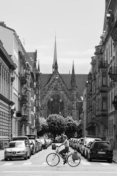 Black and white photo of a cyclist on a street in Strasbourg, featuring a cathedral backdrop.