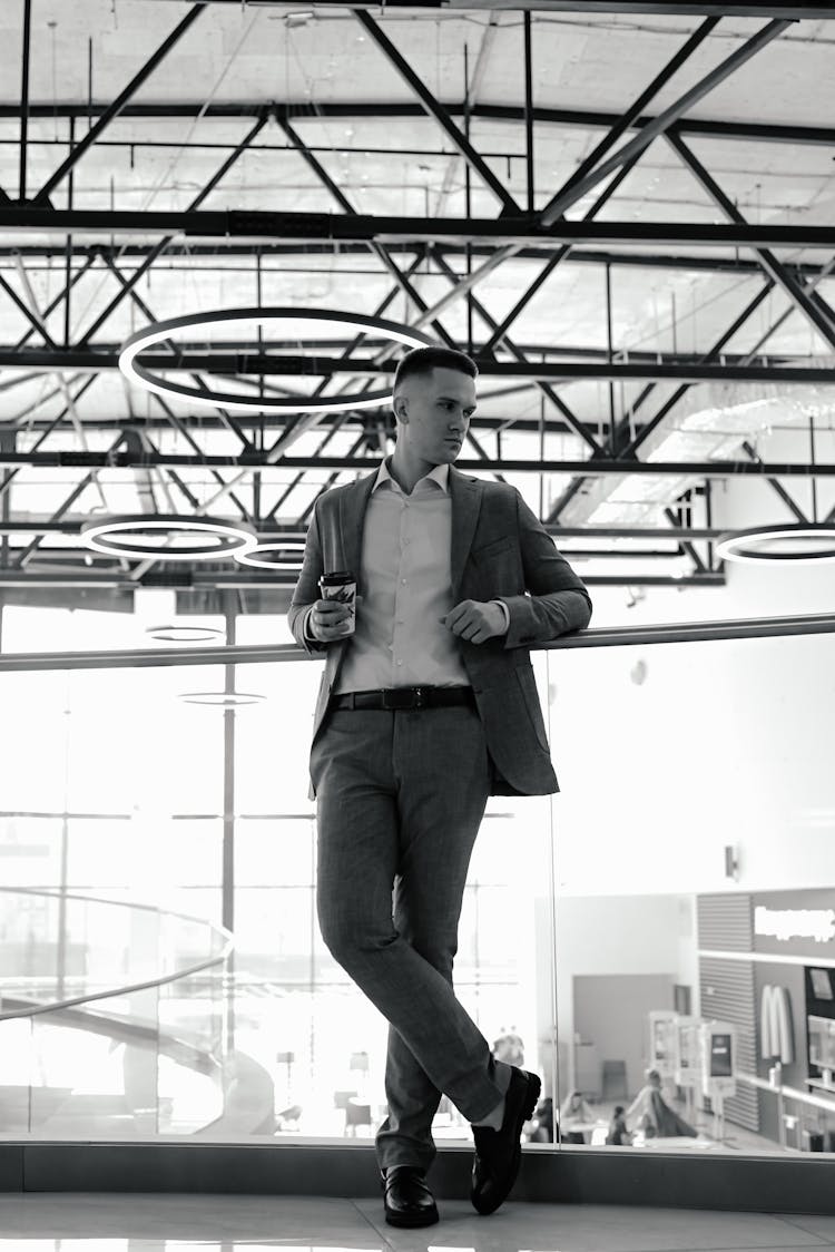 A Man Leaning On A Glass Balustrade