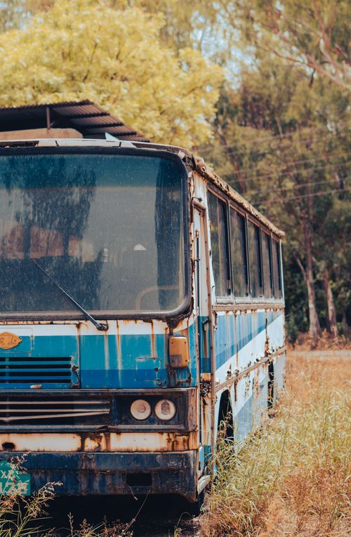 Free An old, rusty bus surrounded by grass in a rural setting, capturing a rustic and decayed charm. Stock Photo