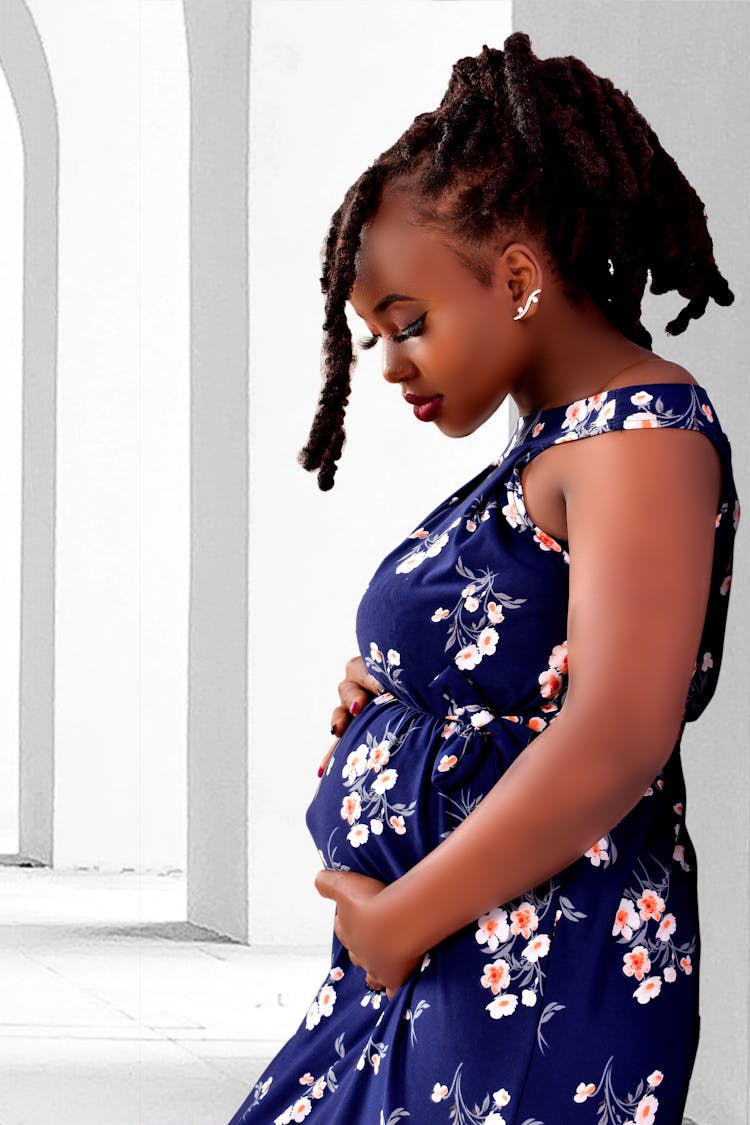 A Pregnant Woman In Floral Dress Holding Her Tummy