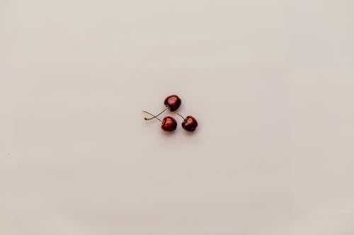 Three Red Cherry Fruits on White Surface