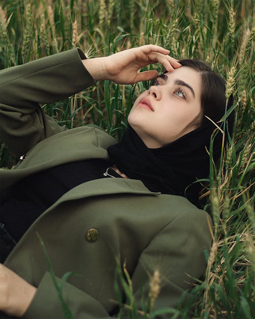 Woman with Headscarf and Green Jacket Lying in Grass