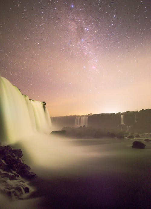 Long Exposure of a Waterfall Under a Starry Night Sky 