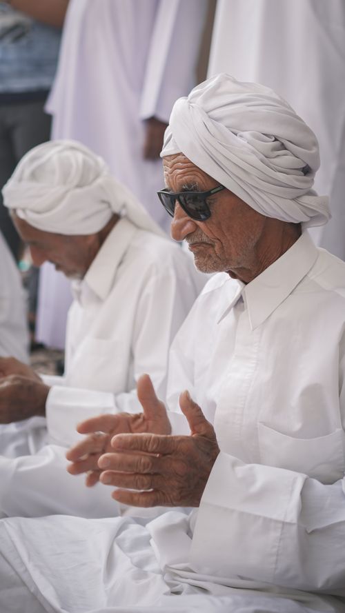 Free Elderly men participate in a traditional celebration, wearing white attire and turbans. Stock Photo