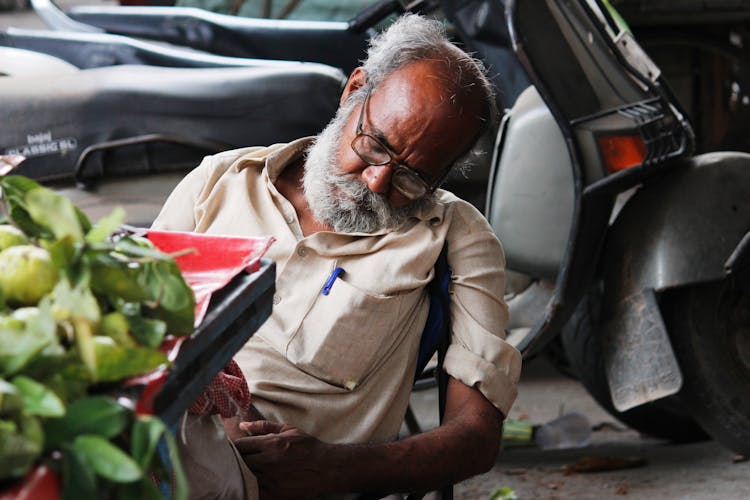 Old Man Sleeping Near Street Stall