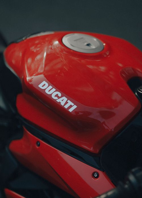 Free Close-up image of the iconic red Ducati motorcycle gas tank with reflective finish. Stock Photo