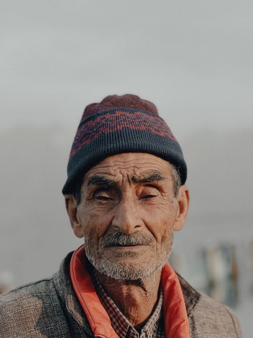 Free Portrait of an elderly man wearing a beanie and warm clothing, with a focus on facial details. Stock Photo