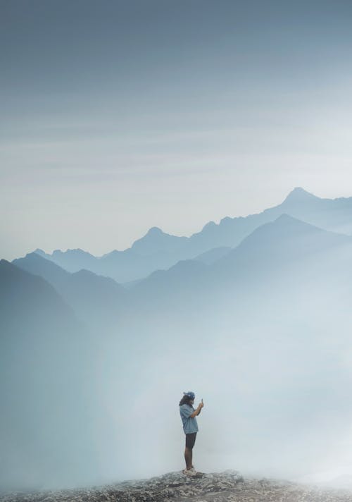 Free Man Standing on Misty Mountain Peak Stock Photo