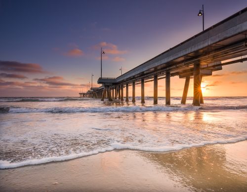 Free Beautiful sunrise view of a pier over the ocean in Dubai, UAE, with waves on the sandy beach. Stock Photo