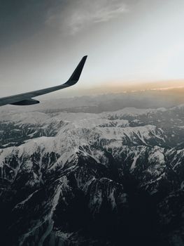 Stunning aerial view of snowcapped mountains at dusk with an airplane wing.