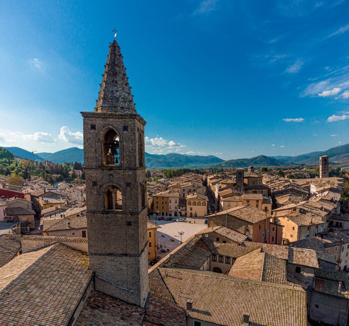 A breathtaking aerial view of Urbino's medieval architecture under a blue sky.