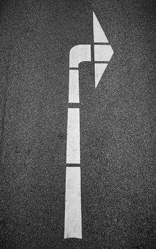 Detailed image of a white right turn arrow on asphalt surface.