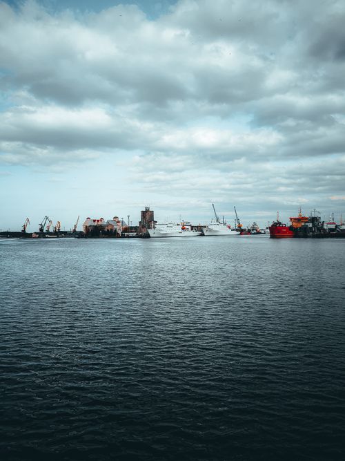 Free A breathtaking view of a harbor with boats and cranes under a cloudy sky, ideal for maritime themes. Stock Photo
