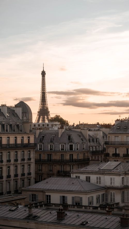 Free Serene view of the Eiffel Tower at sunset, surrounded by classic Parisian architecture. Stock Photo